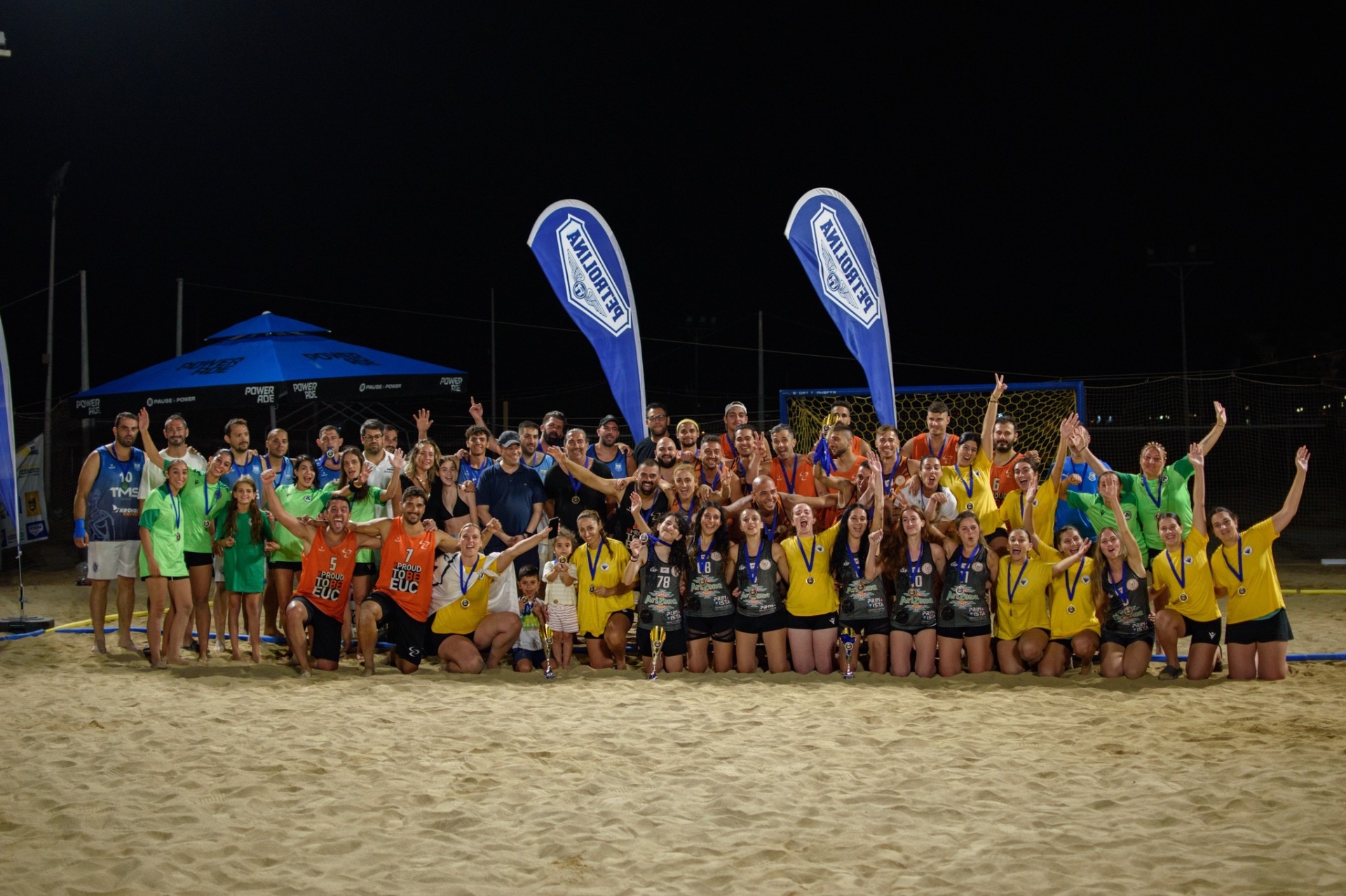 All teams group photo with medals at night